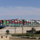 A picture taken on March 29, 2021 shows the Panama-flagged MV ‘Ever Given’ container ship (background) after being fully dislodged from the banks of the Suez Canal, near Suez city. - The vessel, a megaship the length of four football fields, was refloated and the Suez Canal reopened to traffic in the afternoon, sparking relief almost a week after the huge container ship got stuck and blocked a major artery for global trade.